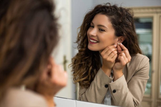 woman accessorizing for outfit by putting earrings on