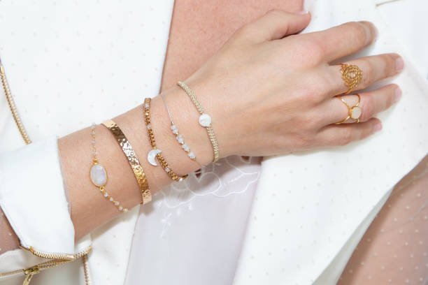layering and stacking accessories on woman neck with hand with many bracelets